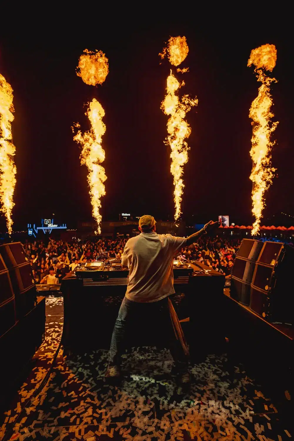 DJ Nano con el brazo en alto ante el público, con llamaradas sobre el escenario