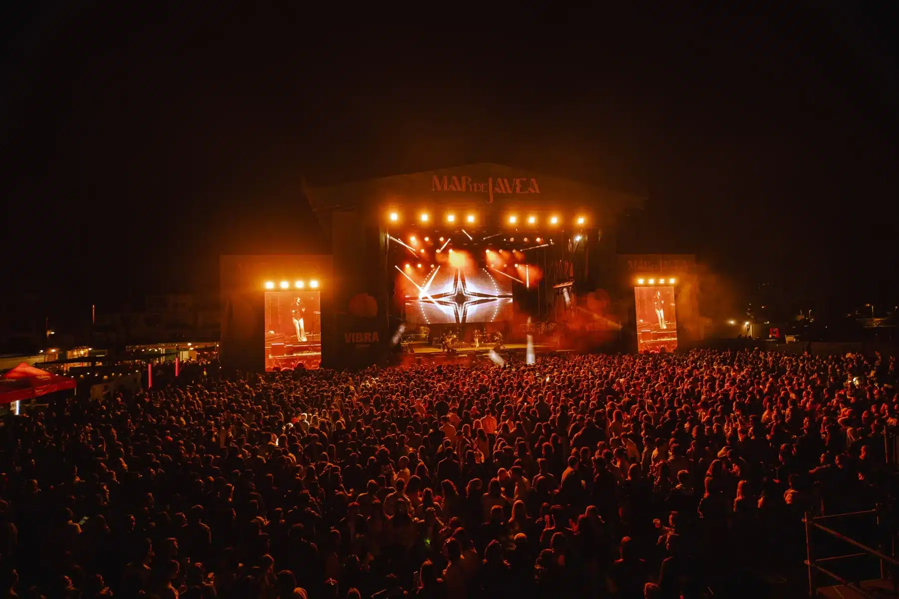 Público y escenario de Mar de Jávea iluminado en rojo durante un concierto nocturno
