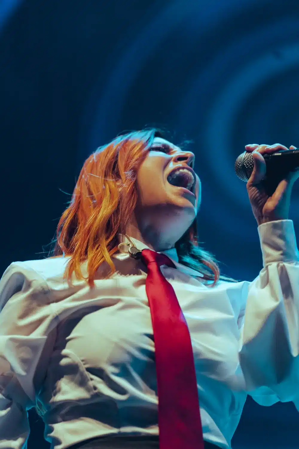 La cantante Leire Martínez con corbata roja en pleno concierto bajo luz azul